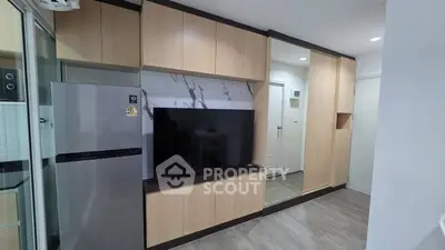 Modern apartment interior with sleek wooden cabinetry and large flat-screen TV.