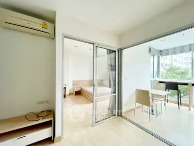 Modern apartment with open layout, featuring a cozy bedroom and a bright dining area with balcony view.