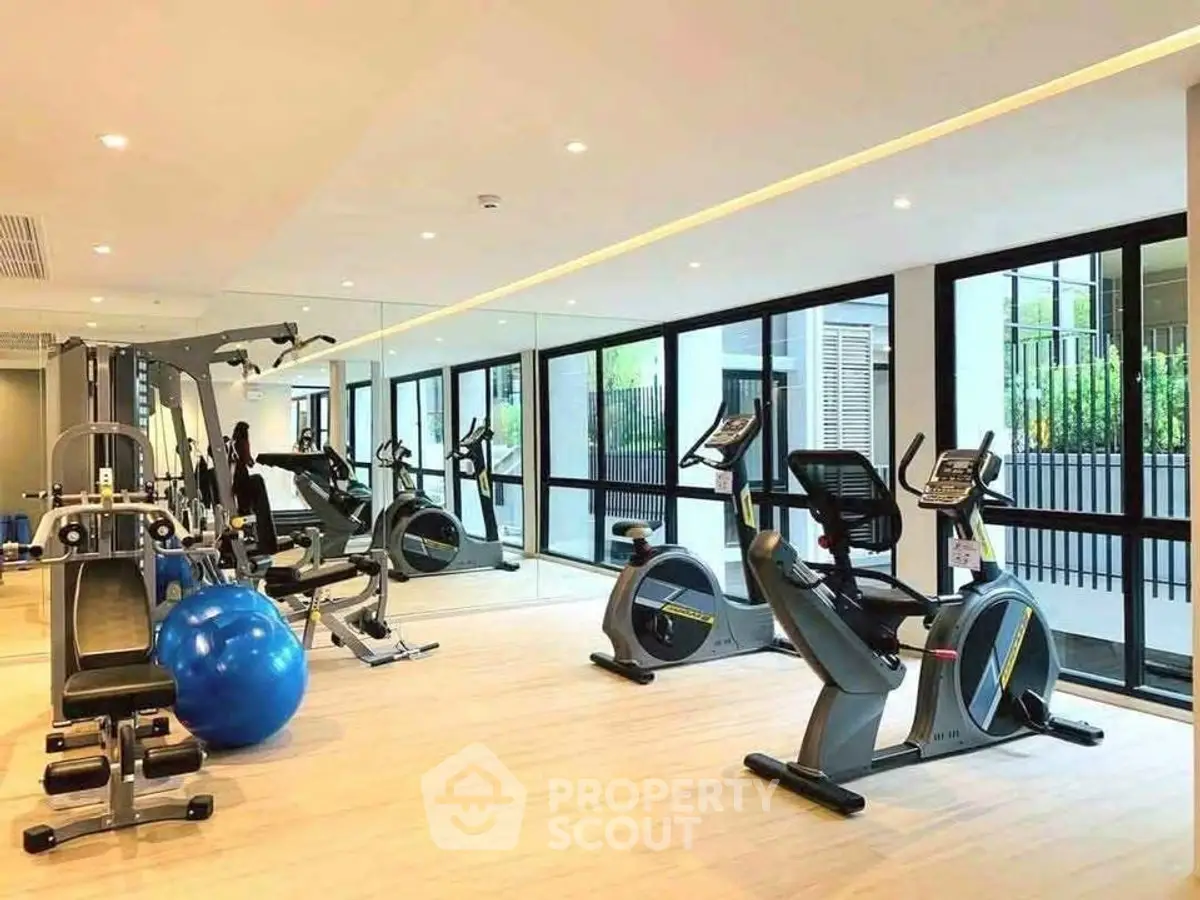 Modern gym with state-of-the-art equipment and large windows in a luxury residential building.