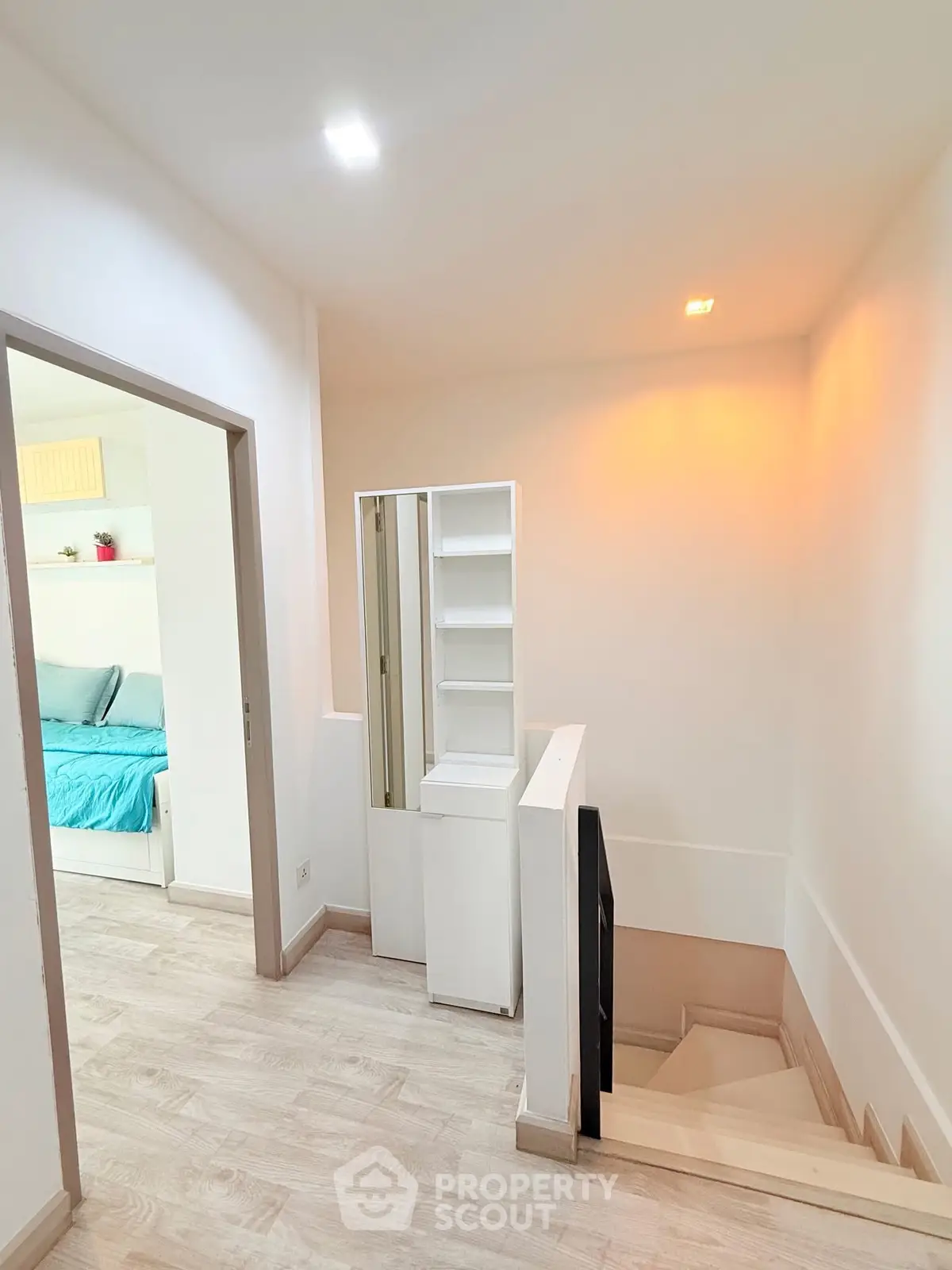 Modern interior hallway with wooden flooring and built-in storage leading to a cozy bedroom.