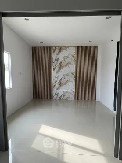 Spacious modern room with elegant marble accent wall and sleek tile flooring, perfect for stylish living.