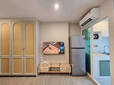Modern living room with TV, fridge, and air conditioning in stylish apartment.