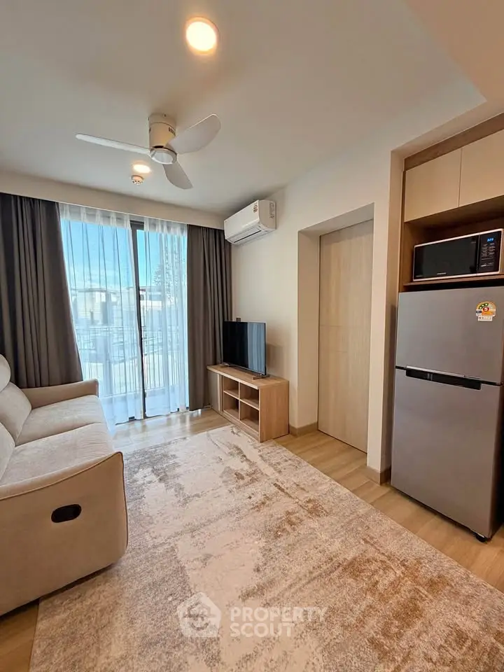 Modern living room with cozy sofa, TV, and balcony access in stylish apartment.