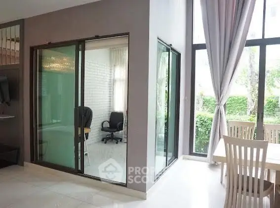 Modern living room with glass-enclosed study area and large windows for natural light.
