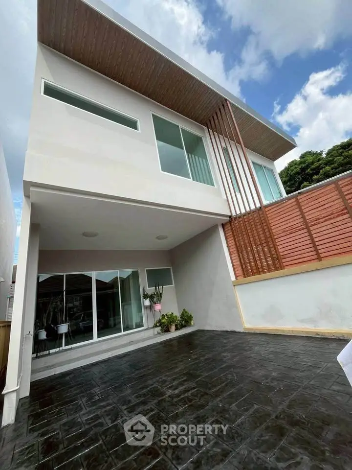 Modern two-story house with sleek design and spacious outdoor area, featuring large windows and stylish wooden accents.