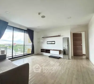 Spacious living room with large windows and balcony access, offering a bright and airy atmosphere.