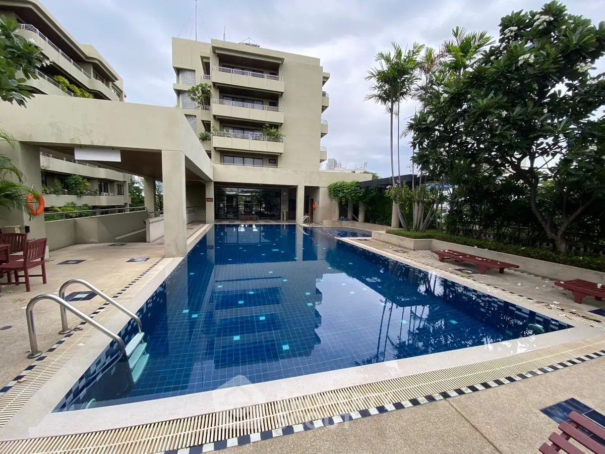 Luxurious residential building with a stunning outdoor pool and lush greenery, perfect for relaxation and leisure.