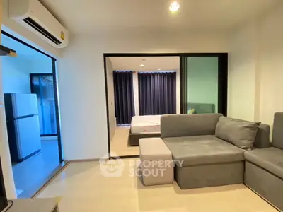 Modern living room with gray sectional sofa and view into bedroom