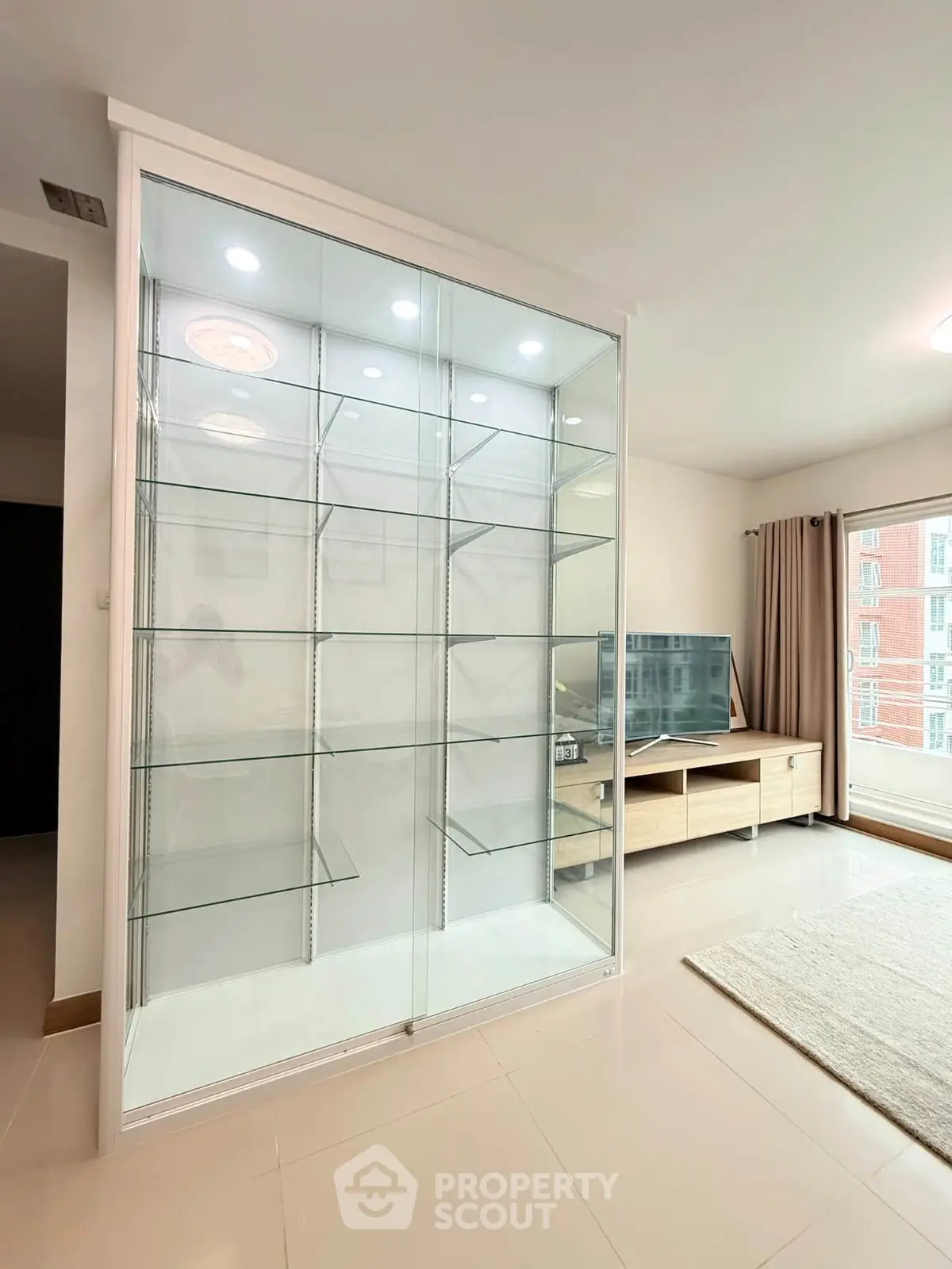 Spacious living room with modern glass display cabinet and large TV unit, perfect for stylish urban living.