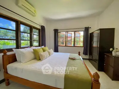 Spacious bedroom with large windows and elegant wooden furniture, offering a serene and inviting atmosphere.