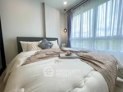 Cozy bedroom with large window and stylish decor, perfect for relaxation.