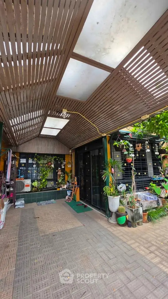 Charming outdoor entrance with wooden pergola and lush greenery, perfect for a welcoming home ambiance.