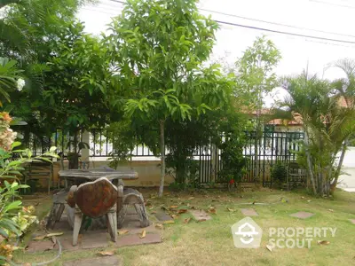 Charming garden with lush greenery and rustic outdoor seating in a serene residential area.