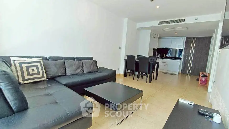 Modern living room with sleek black furniture and open kitchen layout in a stylish apartment.