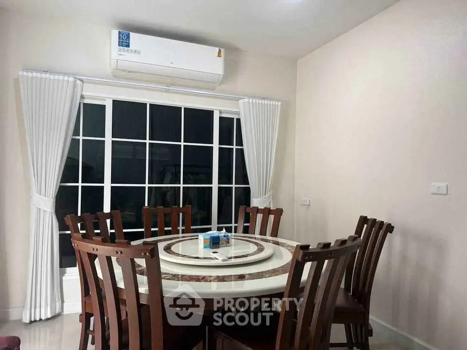 Elegant dining room with wooden furniture and large window, featuring a modern air conditioning unit.
