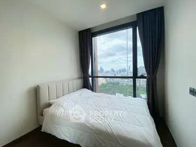 Modern bedroom with city view and large window, featuring a cozy bed and elegant curtains.