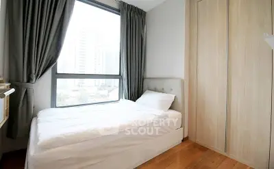 Cozy bedroom with large window and modern furnishings in urban apartment