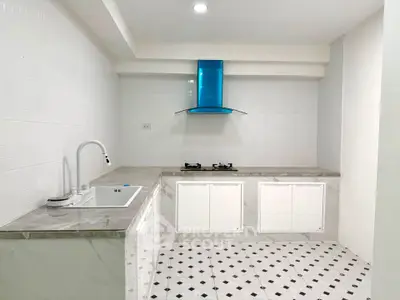 Modern kitchen with sleek design, featuring a gas stove and stylish blue range hood.