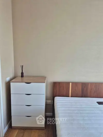 Modern bedroom with minimalist design featuring a wooden bed and sleek white dresser.