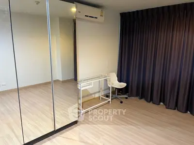 Modern study room with mirrored closet and sleek desk in a minimalist apartment.