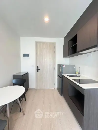 Modern kitchen with sleek cabinetry and compact dining area in a stylish apartment.