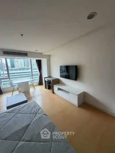 Modern bedroom with city view, featuring sleek furniture and large windows for natural light.