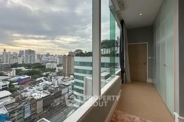 Stunning city view from modern high-rise apartment with floor-to-ceiling windows.