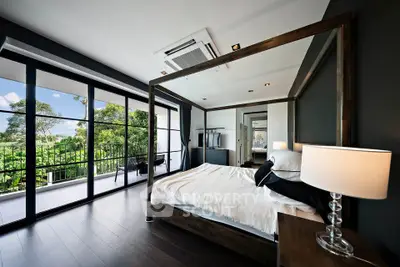 Luxurious bedroom with canopy bed and floor-to-ceiling windows overlooking lush greenery.