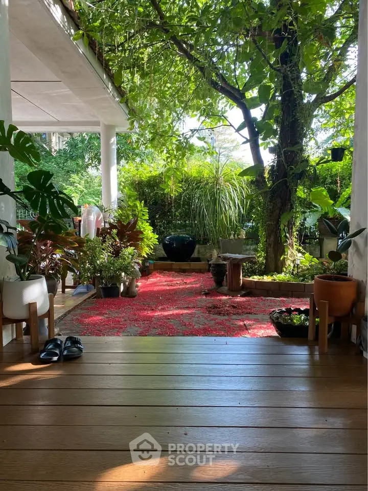 Charming garden view from a cozy wooden deck surrounded by lush greenery and vibrant plants.