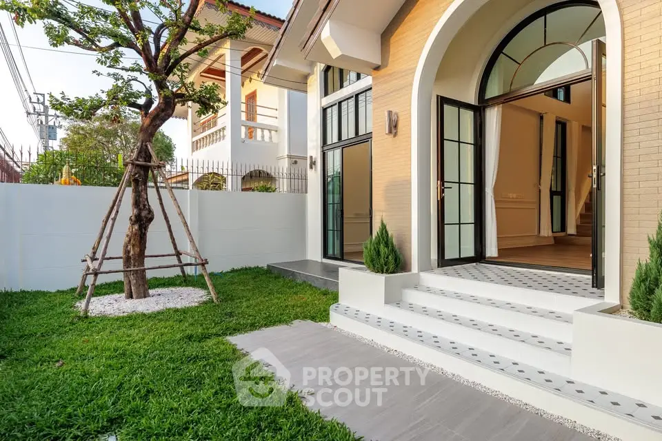 Charming modern home entrance with lush garden and elegant arched doorway, perfect for serene living.