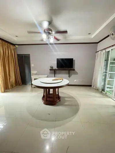 Spacious living room with ceiling fan and large windows, perfect for natural light.