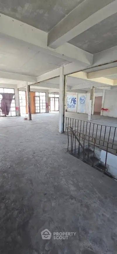 Spacious industrial loft with open floor plan and large windows, ideal for creative workspace or urban living.