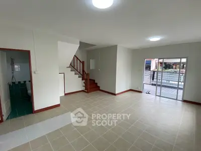 Spacious open-plan living area with staircase and sliding glass doors to balcony.