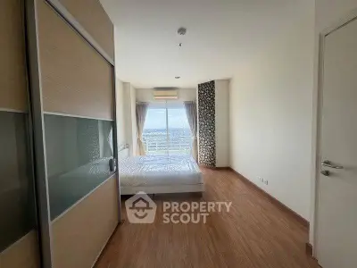 Spacious bedroom with wooden flooring and large window offering natural light and scenic views.