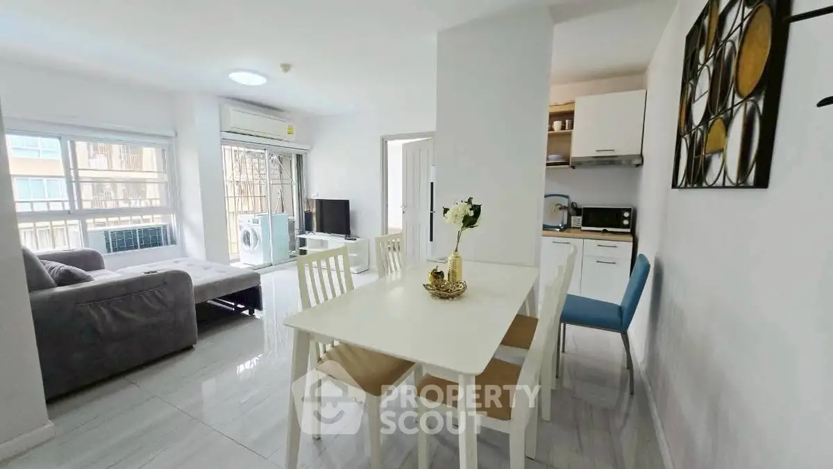 Modern open-plan living room with dining area and kitchen, featuring sleek furniture and bright natural light.