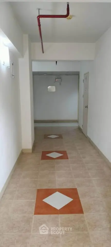 Spacious corridor with tiled flooring and modern lighting in a residential building.