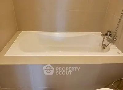 Modern bathroom with sleek bathtub and neutral tile design.