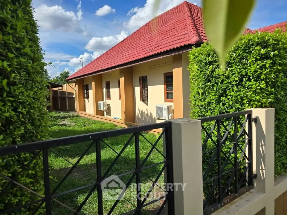 Charming single-story home with red roof and lush garden, perfect for serene living.