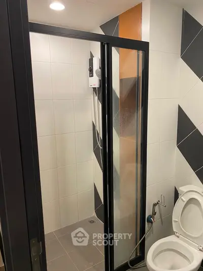 Modern bathroom with glass shower door and geometric tile design
