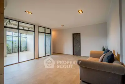 Spacious modern living room with large windows and cozy sofa, perfect for relaxation and entertaining.