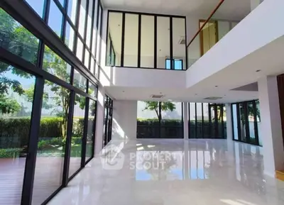 Spacious modern living room with floor-to-ceiling windows and garden view.