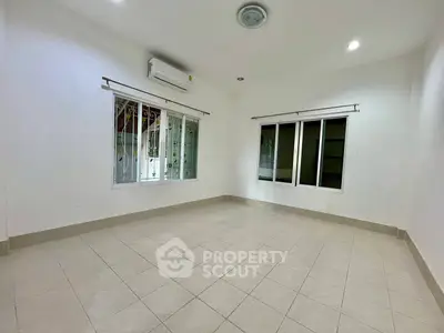 Spacious empty room with tiled flooring and large windows, perfect for customization.