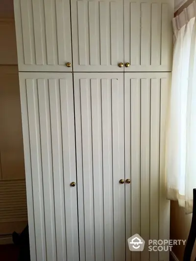 Elegant built-in wardrobe with classic panel doors and brass knobs in a bright room.