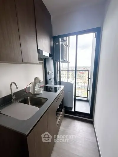 Compact modern kitchen with balcony view, featuring sleek cabinetry and appliances.