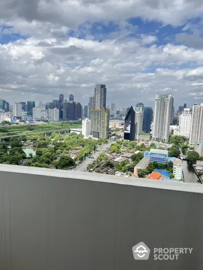 Stunning cityscape view from high-rise balcony overlooking urban skyline and lush greenery.