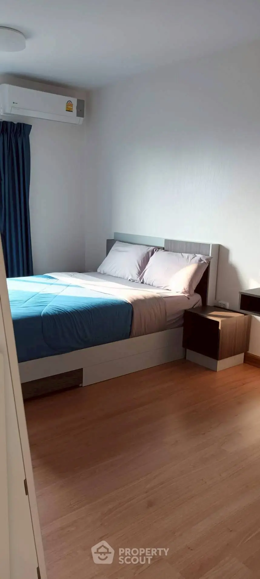 Modern bedroom with wooden flooring and air conditioning unit