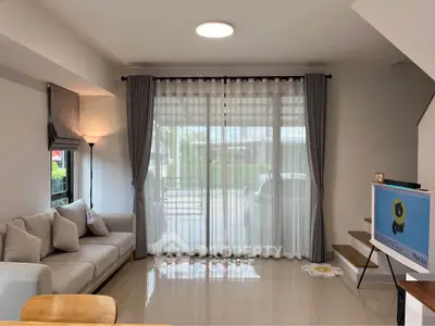 Modern living room with large window, cozy sofa, and stylish decor