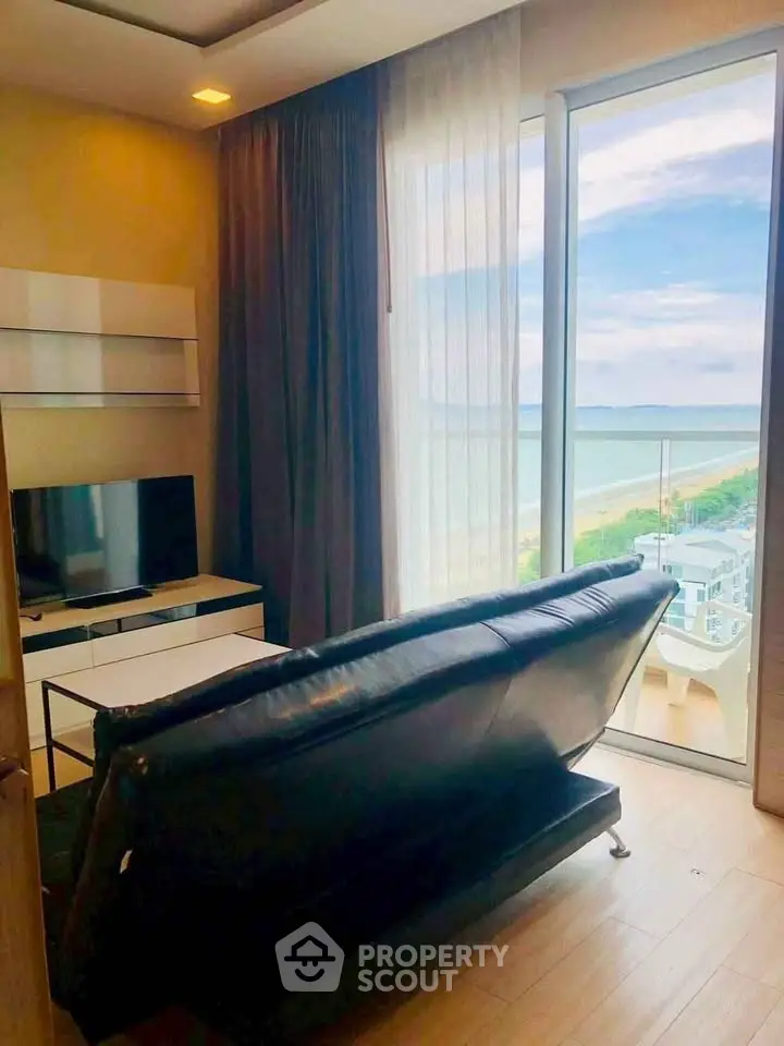 Stylish living room with ocean view, modern furniture, and floor-to-ceiling windows in a high-rise apartment.