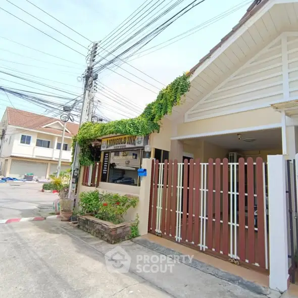 Charming suburban house with lush greenery and gated entrance in a quiet neighborhood.