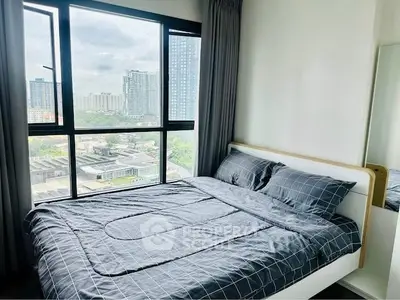 Modern bedroom with large window offering city view in high-rise apartment.